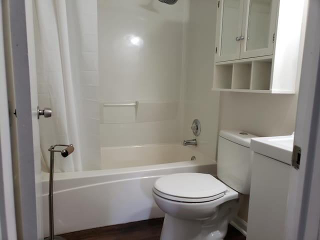 full bathroom with hardwood / wood-style floors, vanity, toilet, and shower / bathtub combination with curtain