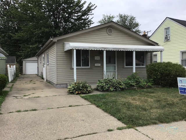 view of front of home featuring a garage, a front lawn, and an outbuilding