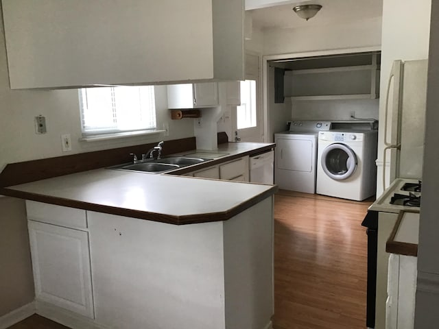 kitchen with white cabinets, kitchen peninsula, washer and clothes dryer, dark hardwood / wood-style floors, and white appliances