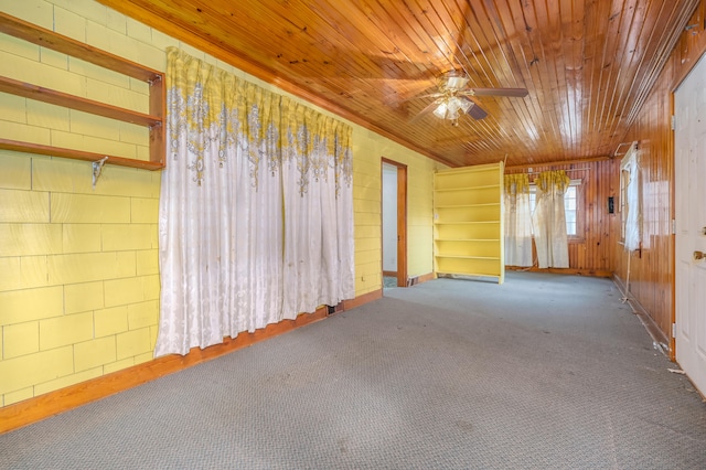 carpeted spare room with ceiling fan, wood ceiling, and wooden walls