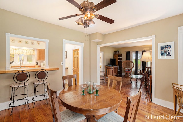 dining room with ceiling fan, sink, and light hardwood / wood-style floors