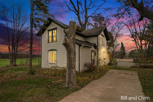 property exterior at dusk with central AC unit and a yard