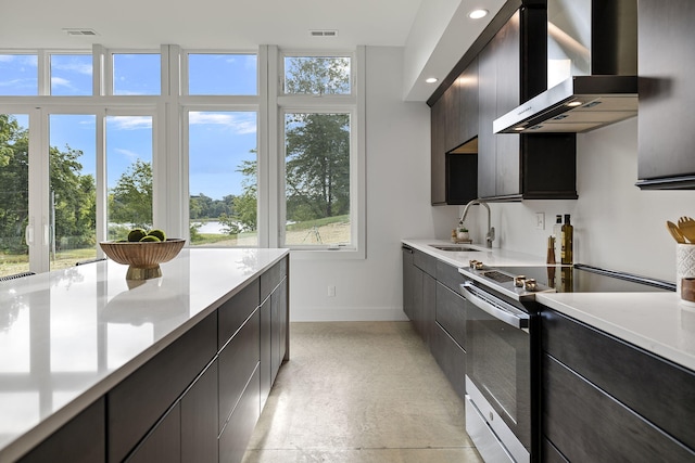 kitchen featuring dark brown cabinets, wall chimney exhaust hood, sink, and stainless steel range with electric cooktop