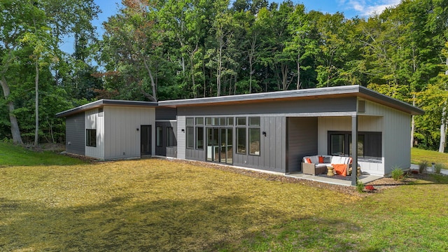 rear view of house with an outdoor living space, a lawn, and a patio