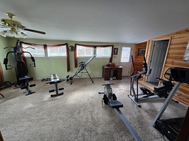 exercise room featuring wood walls, lofted ceiling, ceiling fan, and carpet floors