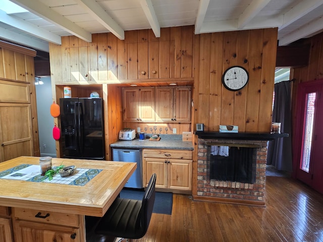 kitchen featuring black fridge, beamed ceiling, stainless steel dishwasher, dark hardwood / wood-style floors, and a fireplace