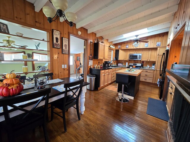 kitchen featuring stainless steel appliances, sink, beam ceiling, a kitchen island, and dark hardwood / wood-style flooring