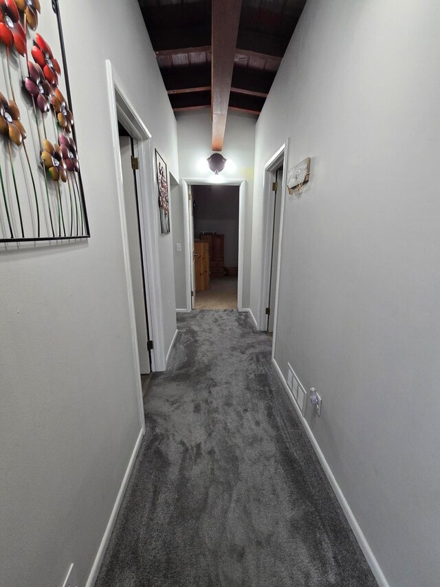 hallway with dark colored carpet, beamed ceiling, and wooden ceiling