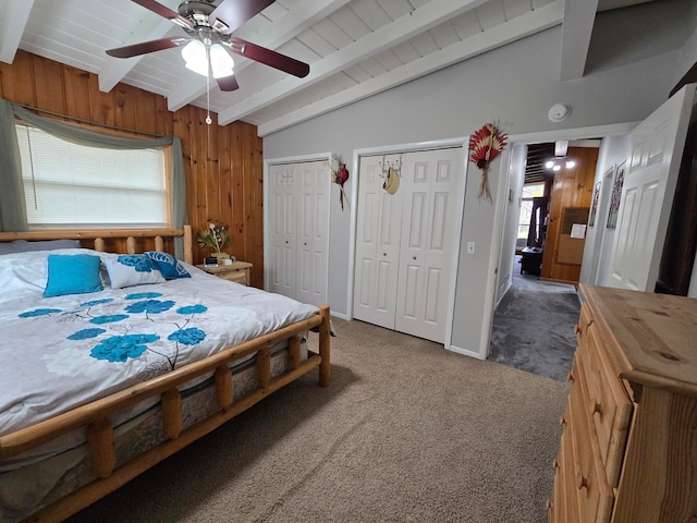 carpeted bedroom with wood walls, ceiling fan, wood ceiling, and vaulted ceiling with beams