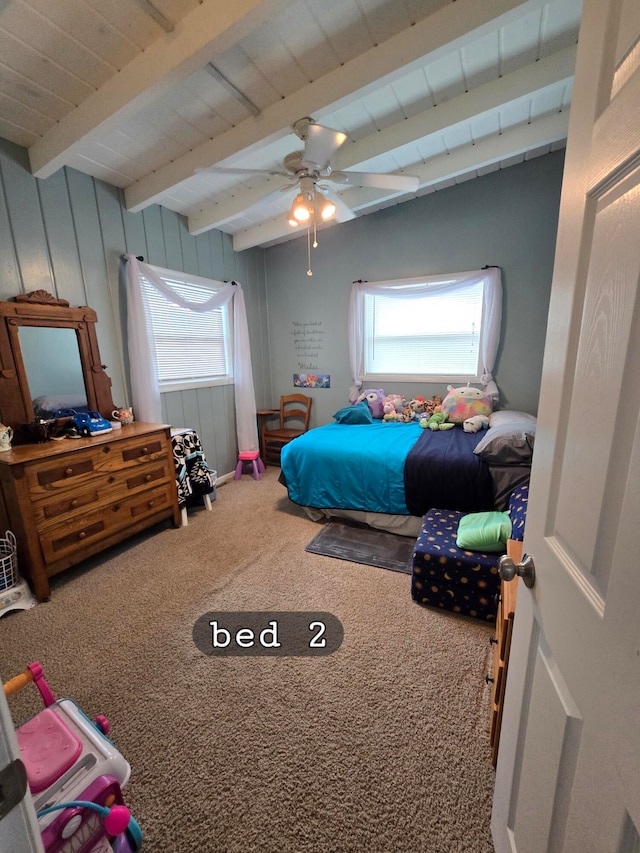 carpeted bedroom with ceiling fan, multiple windows, and beam ceiling