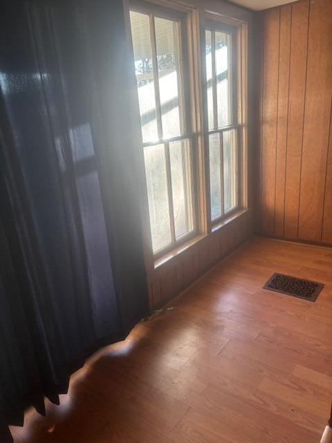 empty room featuring wood-type flooring and wooden walls