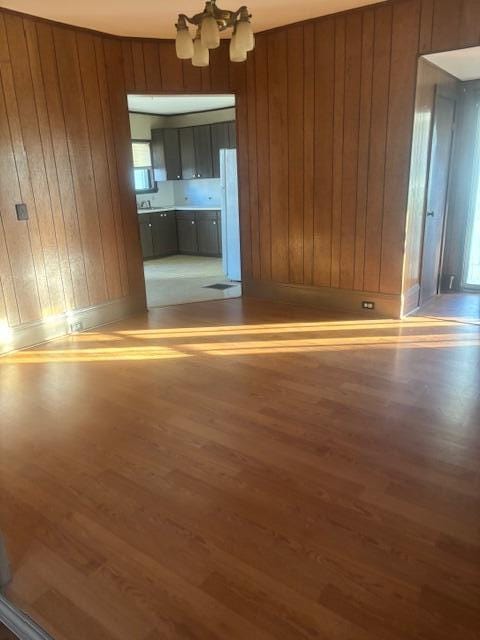 interior space featuring wooden walls, hardwood / wood-style flooring, and a notable chandelier