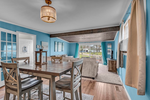 dining area with wood-type flooring and beam ceiling