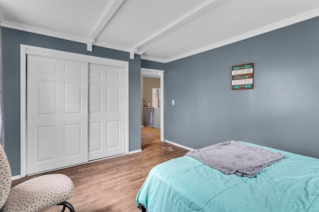 bedroom with a closet, beamed ceiling, hardwood / wood-style flooring, and crown molding