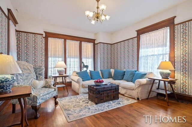 living room with wood-type flooring, a healthy amount of sunlight, and an inviting chandelier