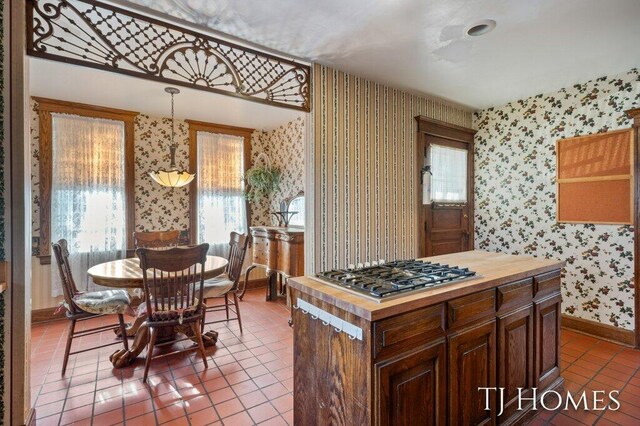 kitchen featuring tile patterned floors, hanging light fixtures, stainless steel gas cooktop, and butcher block counters