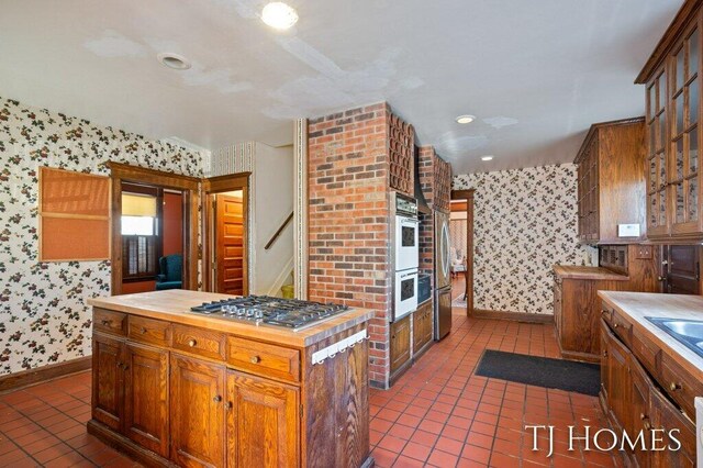 kitchen featuring dark tile patterned flooring, stainless steel gas stovetop, and a kitchen island