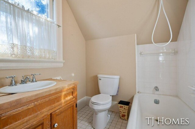 full bathroom featuring vanity, tiled shower / bath combo, vaulted ceiling, tile patterned flooring, and toilet