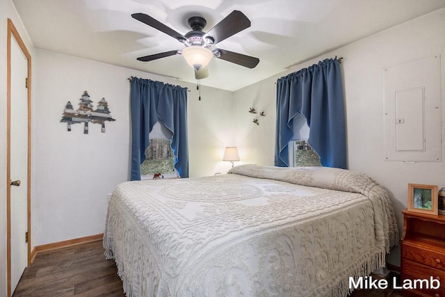 bedroom with dark wood-type flooring, ceiling fan, and electric panel