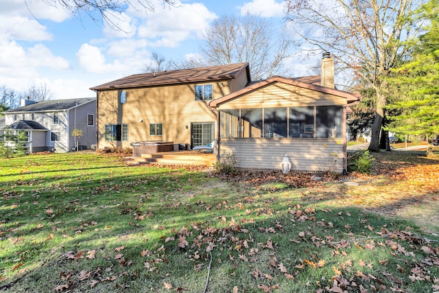 back of house featuring a sunroom, a yard, a hot tub, and a patio area