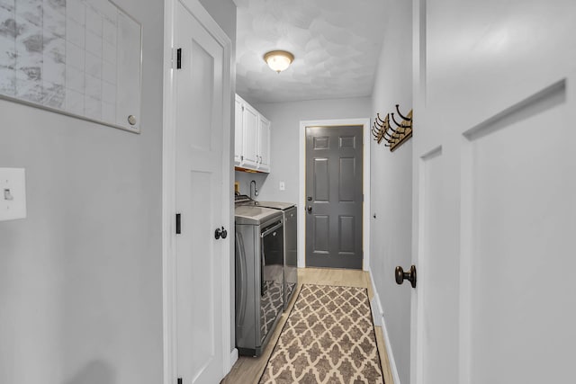 washroom featuring separate washer and dryer, light hardwood / wood-style flooring, and cabinets