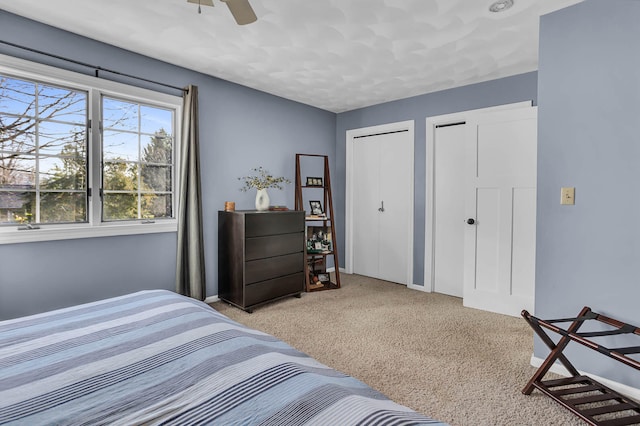 carpeted bedroom featuring two closets and ceiling fan