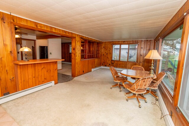 carpeted dining room featuring a baseboard heating unit and wood walls