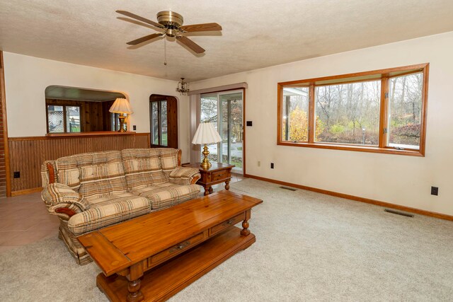 living room with ceiling fan, light colored carpet, and a textured ceiling