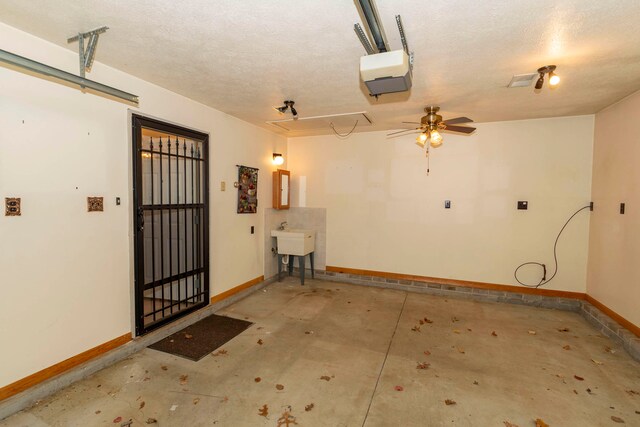 garage with electric panel, a garage door opener, ceiling fan, and sink