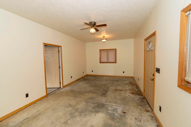 spare room featuring a textured ceiling, ceiling fan, and concrete floors