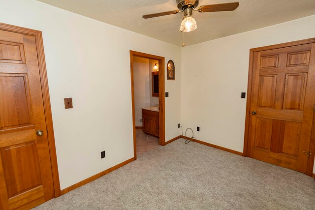 unfurnished bedroom with ensuite bathroom, ceiling fan, light carpet, and a textured ceiling