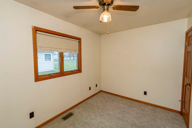 unfurnished room featuring a textured ceiling, ceiling fan, and light carpet