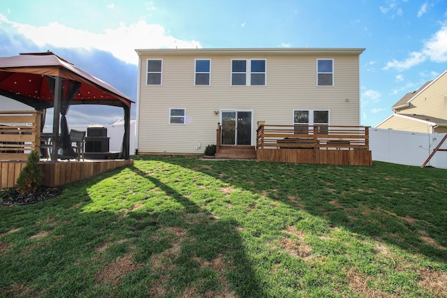 rear view of property with a gazebo, a wooden deck, and a lawn