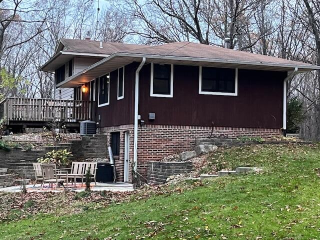 view of side of property featuring a lawn, a deck, and a patio