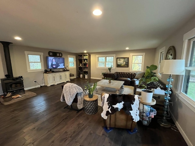 living room with dark hardwood / wood-style floors, a wood stove, and a wealth of natural light