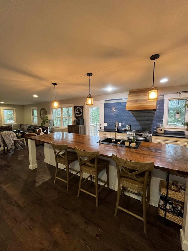 bar featuring high end range, decorative backsplash, premium range hood, and dark wood-type flooring