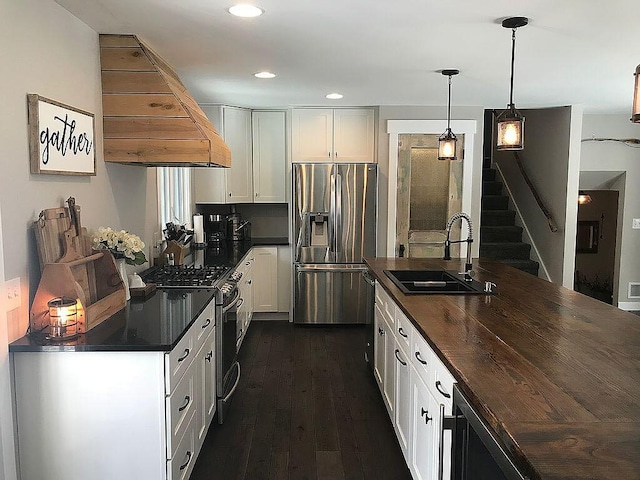 kitchen with sink, white cabinets, custom exhaust hood, and appliances with stainless steel finishes