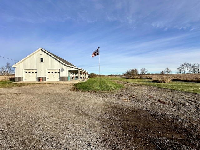 view of home's exterior featuring a rural view, a garage, and an outdoor structure