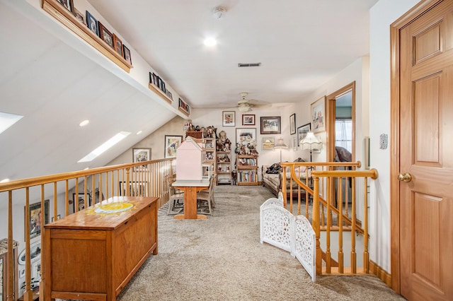 interior space with light carpet, ceiling fan, and vaulted ceiling with skylight