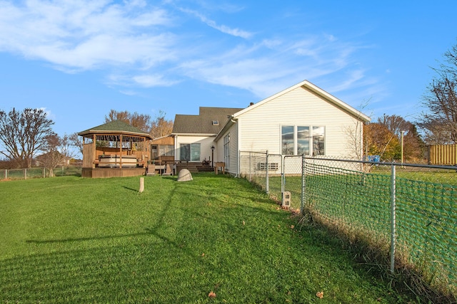 rear view of property featuring a wooden deck and a lawn