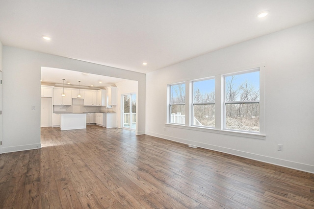 unfurnished living room with hardwood / wood-style flooring, visible vents, baseboards, and recessed lighting