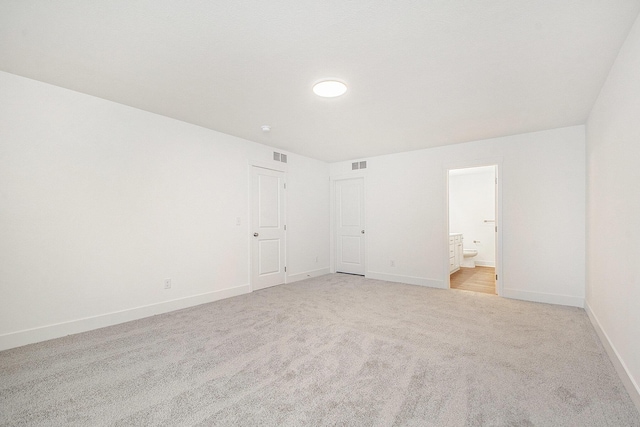 spare room with baseboards, visible vents, and light colored carpet