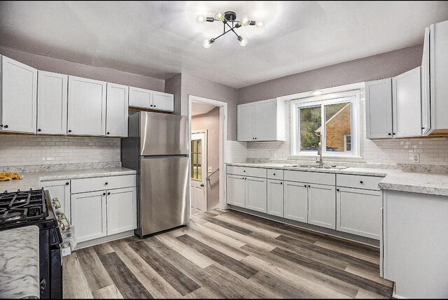 kitchen with white cabinets, stainless steel refrigerator, and black gas stove