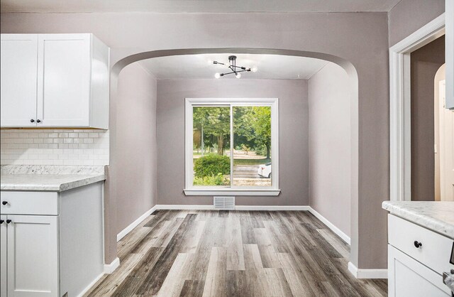 unfurnished dining area featuring wood-type flooring and a chandelier