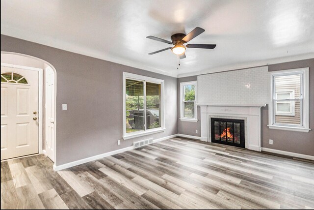 unfurnished living room with ceiling fan, a large fireplace, and light hardwood / wood-style flooring