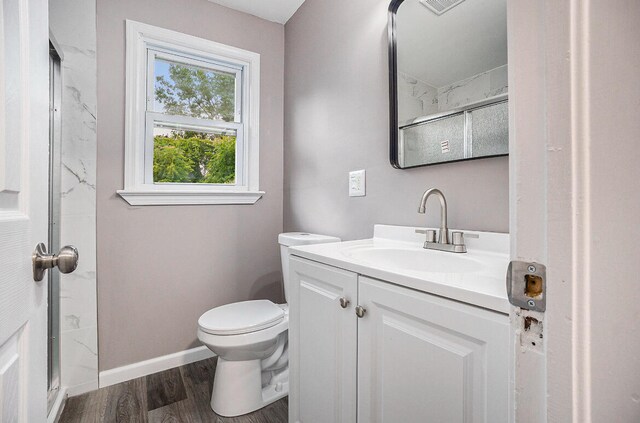 bathroom with wood-type flooring, vanity, toilet, and a shower with shower door