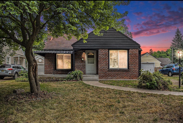 bungalow featuring a garage and a yard