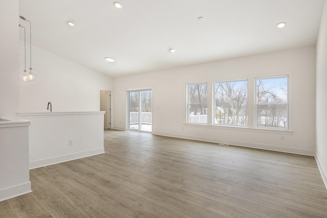 unfurnished room featuring lofted ceiling, light wood finished floors, baseboards, and recessed lighting