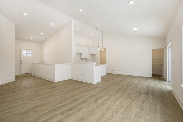 unfurnished living room with high vaulted ceiling, recessed lighting, light wood-style flooring, and baseboards