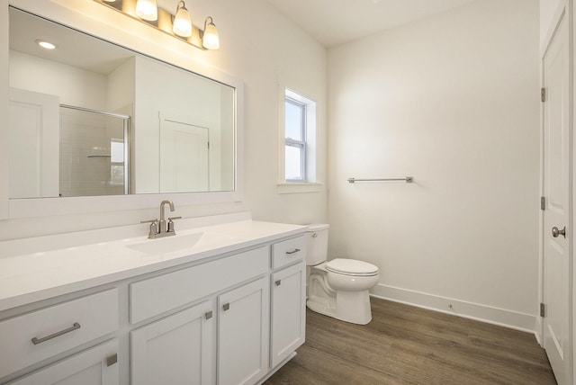 full bathroom with toilet, wood finished floors, vanity, baseboards, and tiled shower